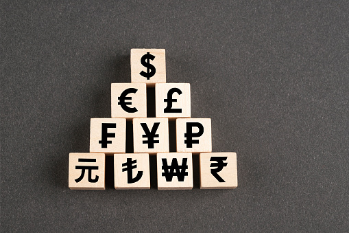 Wooden block cubes with currency symbols on black background