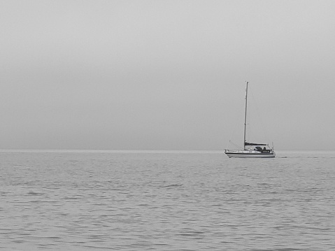 Black and white photography of boat sailing over an ocean under cloudy sky