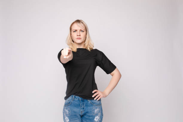 istock Confident young beautiful woman showing by hand stringent looking at camera posing isolated 1395709864