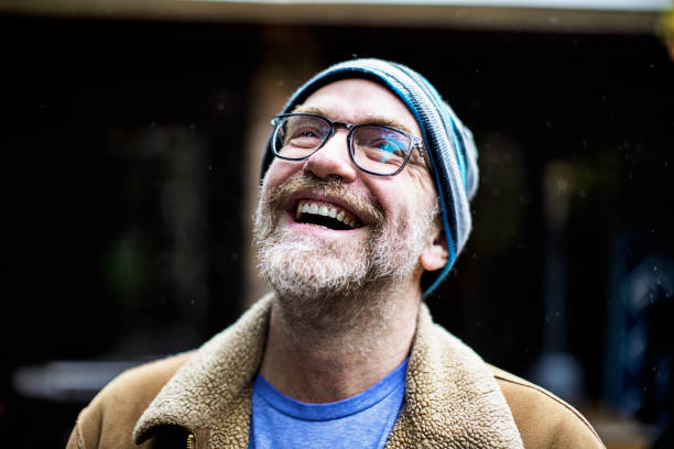 White middle-aged man with a knit hat and glasses laughing