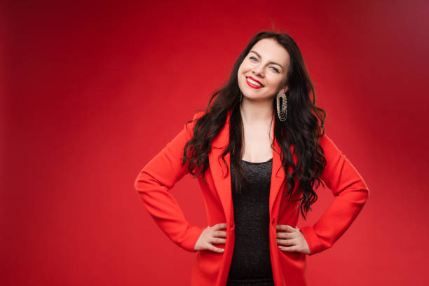 istock Confident brunette in black dress and red jacket posing 1395711097