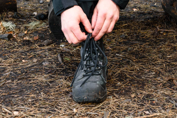 close up of hands tying bootlaces of military styled combat boots - combat boots imagens e fotografias de stock