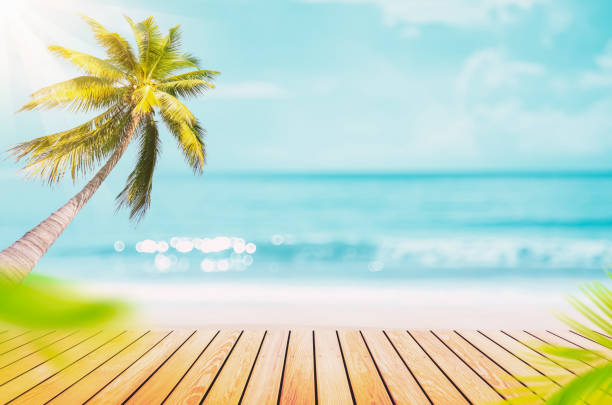istock Blur tropical beach with bokeh sun light wave and palm tree on copy space empty old wood table abstract background. Product presentation in nature. 1395714558