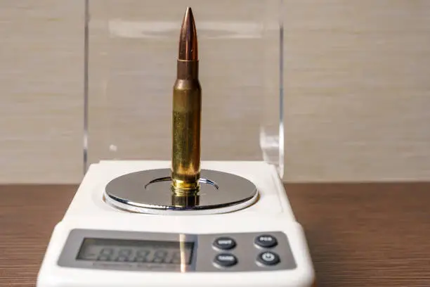 Photo of Large-caliber cartridge for a rifle on the bowl of electronic scales, close-up