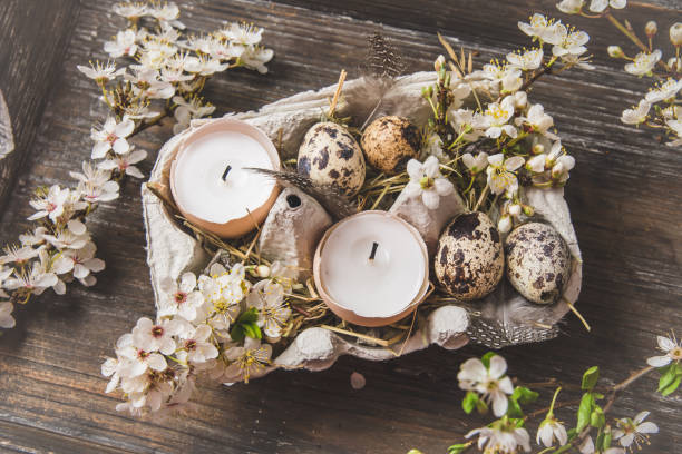 istock Candles in eggshells, quail eggs and white blossoming apple tree branches on a wooden tray as an Easter decoration 1395720885