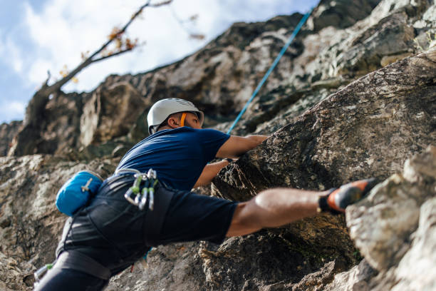 istock Down view, strong man climbing on the rock, moving up fast. 1395727053