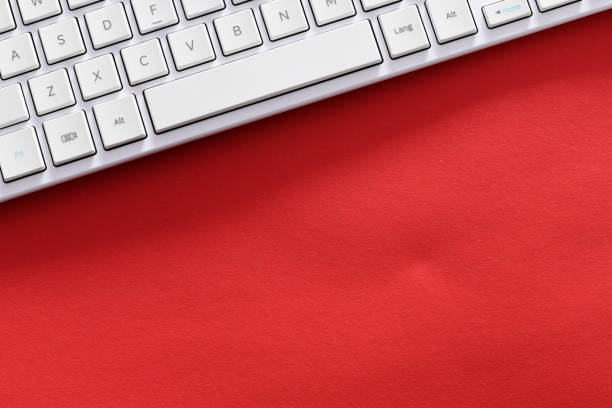 Close up white computer keyboard on red background. View from above.