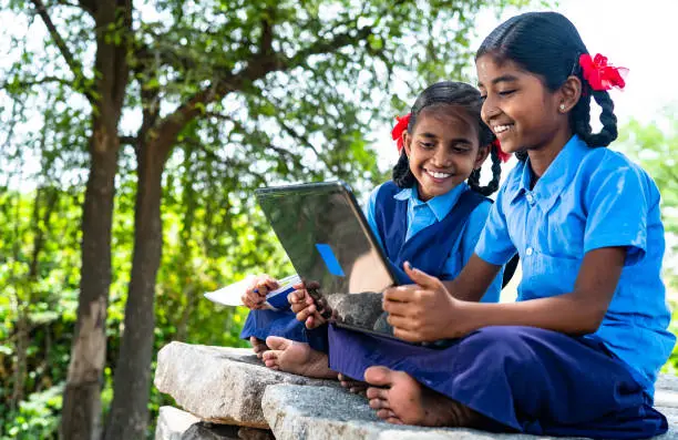 Photo of handheld shot of Village school girl kids seriously busy working on laptop - concept of education, technology and knowledge