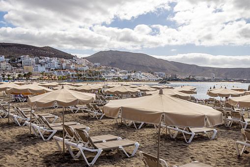 Deck chairs and parasols on the beach at Playa de las Americas which is a popular tourist location on the south coast of the the Spanish Canary Island Tenerife.