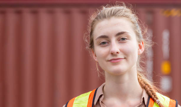 Industrial female engineer with containers box background, Smiling dock worker at containers cargo, Logistic and transportation concepts
