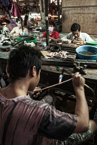 Koh Kong, Cambodia - MARCH 10, 2011: Khmer goldsmith creates necklace and accessories at a gold workshop in Dong Tong Market. Koh Kong.