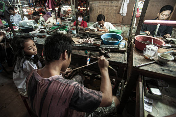 Koh Kong, Cambodia - MARCH 10, 2011: Khmer goldsmith creates necklace and accessories at a gold workshop in Dong Tong Market. Koh Kong.