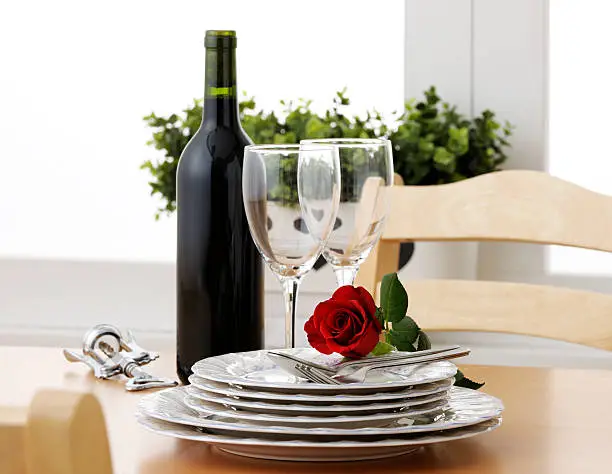 Wine,plate and red rose on wooden table.