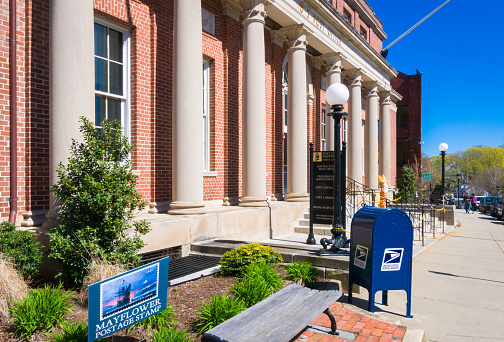 Plymouth, Massachusetts, USA -May 1, 2022-A row of Corinthian columns stand in front of the Post Office Building in Plymouth, Massachusetts that also houses other businesses and displays the recent postage stamp featuring the historic Mayflower.