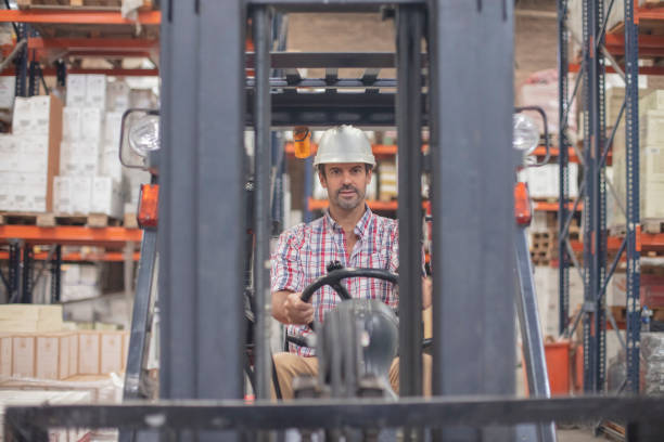 istock Manager wearing protective helmet and driving forklift at distribution warehouse 1395740639
