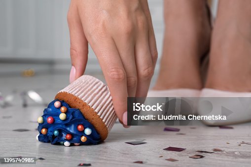 istock Woman picking up dropped cupcake from floor, closeup. Troubles happen 1395740985