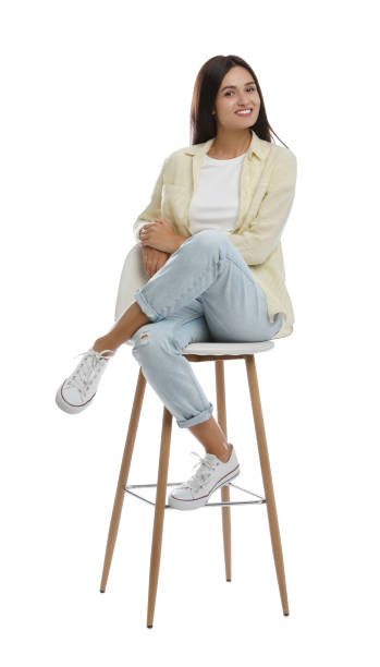 istock Beautiful young woman sitting on stool against white background 1395742034