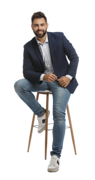 istock Handsome young man sitting on stool against white background 1395742081