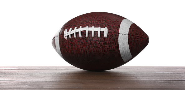 American football ball on wooden table against white background