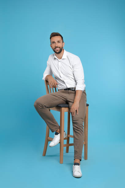 istock Handsome man sitting on stool against turquoise background 1395742271