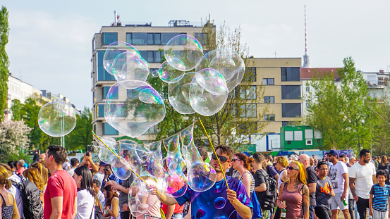 Berlin, Germany-May 2018: Street artist, the entertainer, performing outdoor, making big, beautiful and colourful water bubbles and selling his handmade product, giving joy to the kinds and other people.