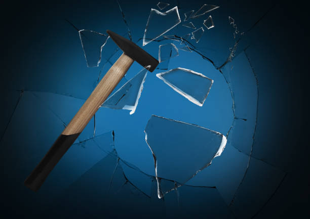 istock Hammer breaking up glass against black background 1395745732