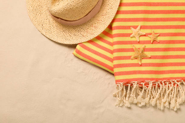 Beach towel, hat and starfishes on sand, flat lay. Space for text