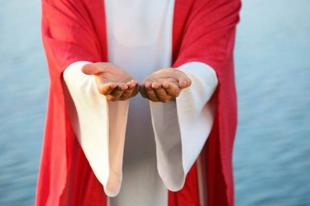 istock Jesus Christ reaching out his hands near water outdoors, closeup 1395748005