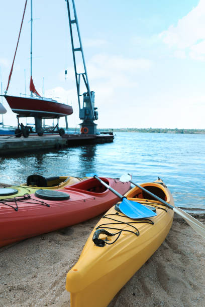istock Modern kayaks with paddles on beach near river. Summer camp activity 1395748255