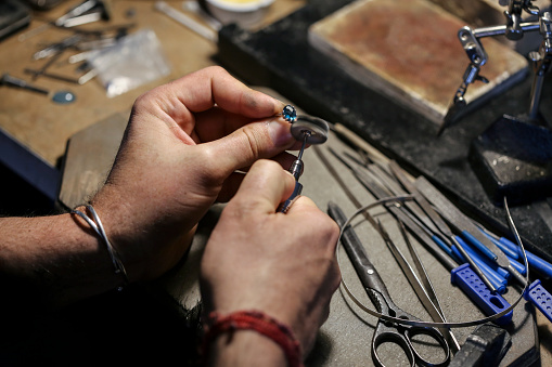 Close-up of an unrecognizable male Caucasian jeweller polishing a ring in his workshop.