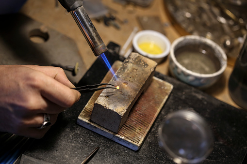 Close-up of an unrecognizable male Caucasian jeweller welding a ring in his workshop.