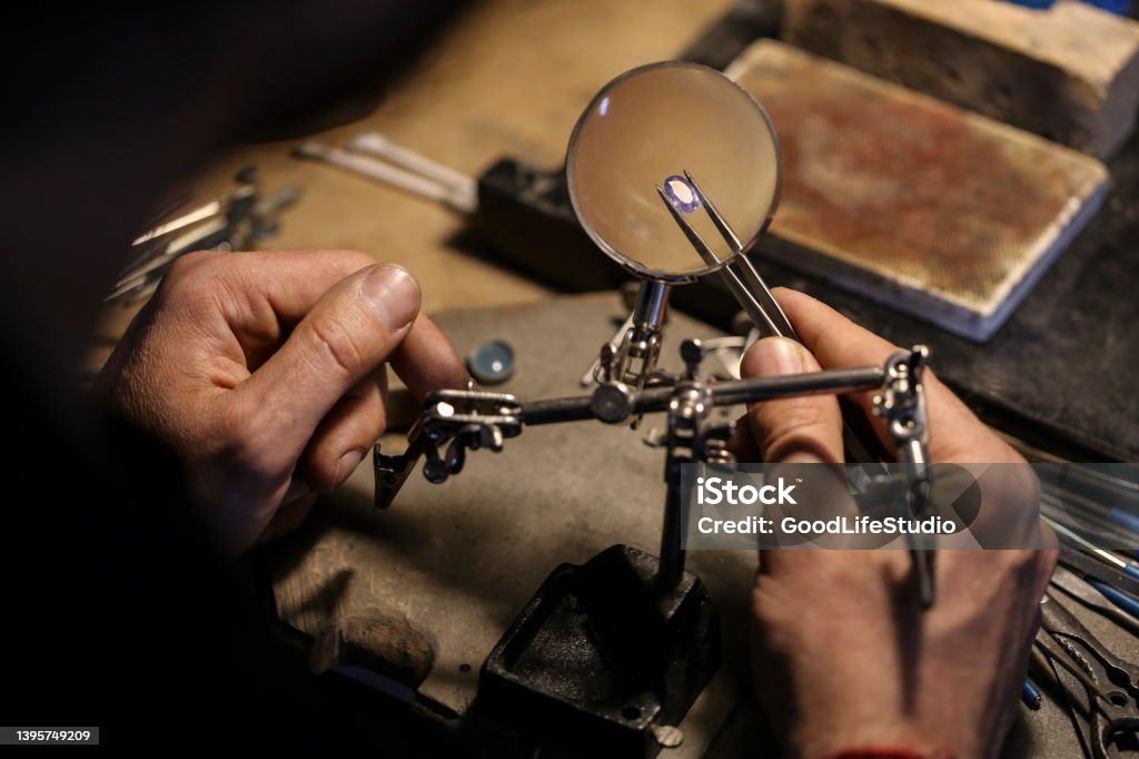 Jeweller examining a gemstone Close-up of an unrecognizable male Caucasian jeweller analyzing a gemstone in his workshop. Jewelry Stock Photo