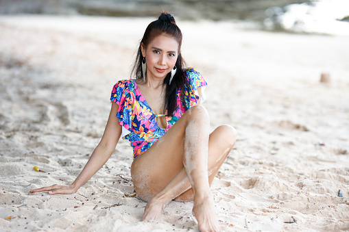 Beautiful long hair and slim woman in bikini posing on sand at beach, leisure activities.