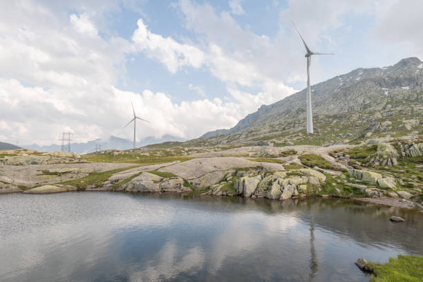 Wind turbines on Gotthard Pass, Switzerland The top of the pass, clouds, reflection on lake surface gotthard pass stock pictures, royalty-free photos & images