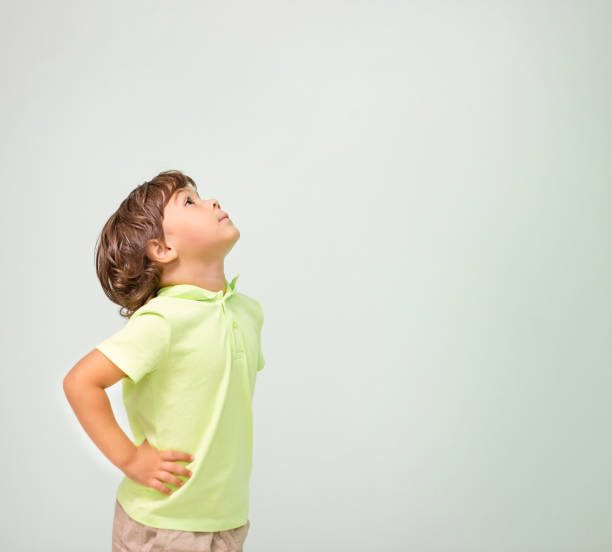little boy stands in profile and looks up