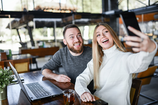Selfie By Smiling Couple Using Laptop In Coffee Bar