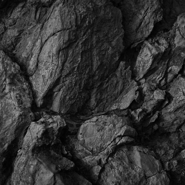 istock Black white rock texture. Rough mountain surface. Close-up. Dark volumetric stone background with space for design. Crumbled. Weathered. 1395756622