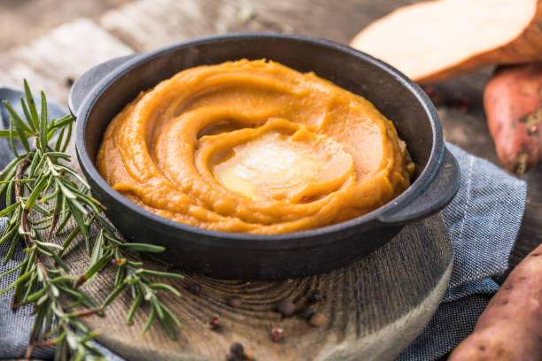 Spicy mashed sweet potato or sweet potato puree with rosemary in a saucepan on a table.  top view from above stock photo