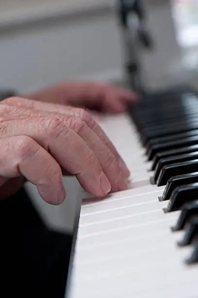 Hand of an old man playing piano. Selective focus. Shallow dept of field.