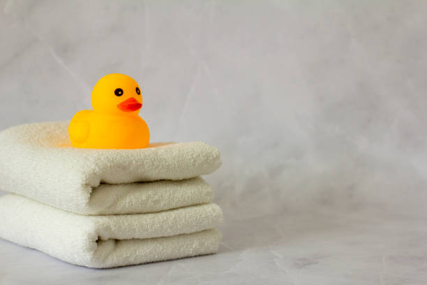 istock A yellow rubber duck for bathing on a stack of clean white towels. 1395760718