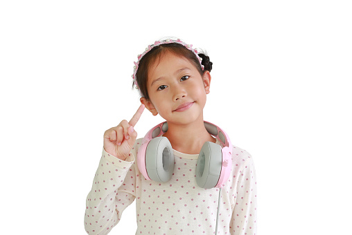 Cute Asian little girl child with headphones on neck show one forefinger isolated on white background.
