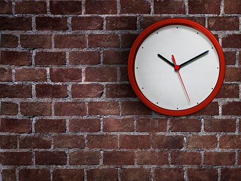 Red clock hang isolated on red brick wall background