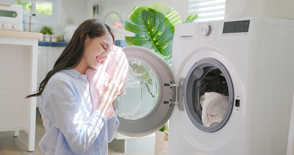 asian brunette long hair smiling woman with clean clothes from washing machine at home