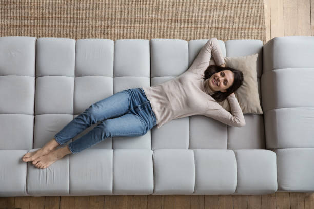 istock Overhead view woman put hands behind head relaxing on sofa 1395762564