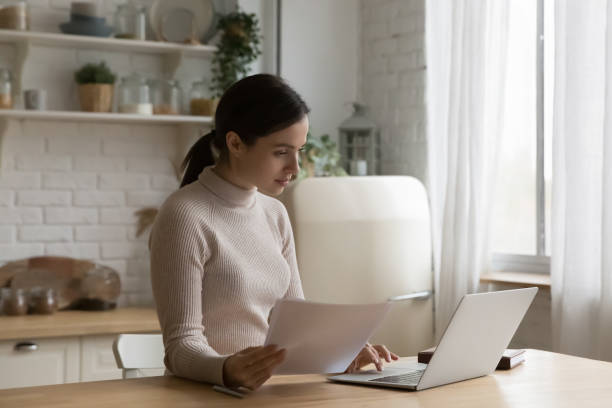 istock Woman holding papers working from home use laptop 1395762590