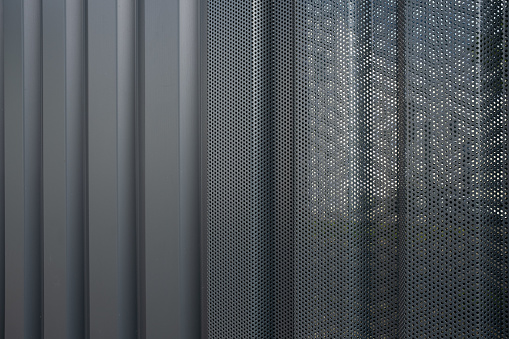 trapezoid aluminum facade cladding with perforated sheet metal in front of the windows.