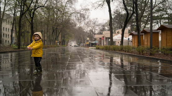Little boy walking outdoors at rainy autumn day