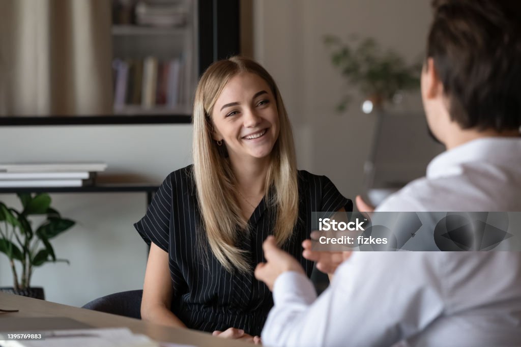 Happy intern listening to mentor, consulting advisor Happy intern listening to mentor, consulting advisor, talking to supervisor, smiling, laughing. Job candidate meeting with employer for interview, discussing vacancy, making good first impression Mentorship Stock Photo