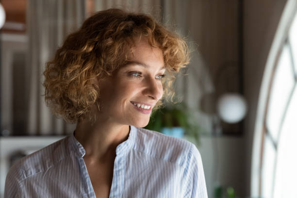 Happy thoughtful businesswoman looking at office window