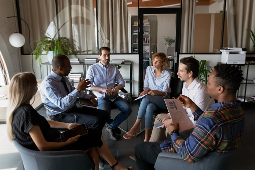 Compañeros de trabajo del equipo de negocios multiétnicos sentados en círculo en la oficina photo